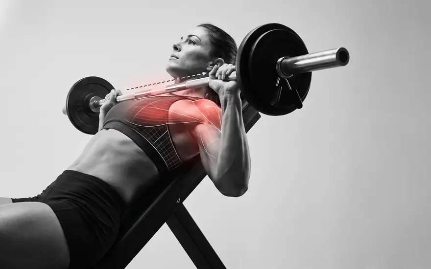 Black-and-white photo of an athlete mid-rep on an incline bench press, with red armour fitted over the upper chest and front shoulder.